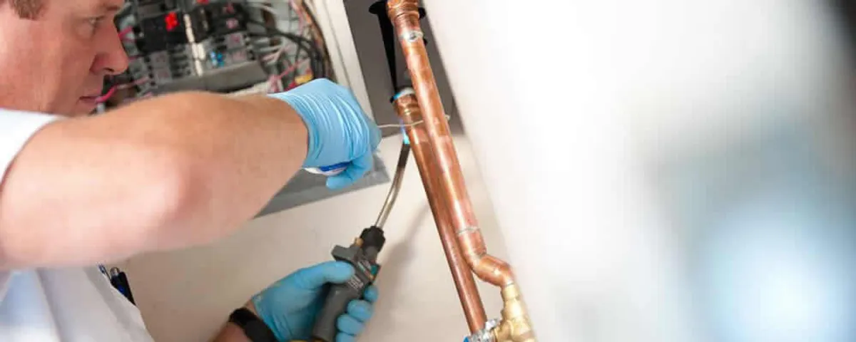 Water heater repair technician testing copper pipe connections and controls in Portland, OR